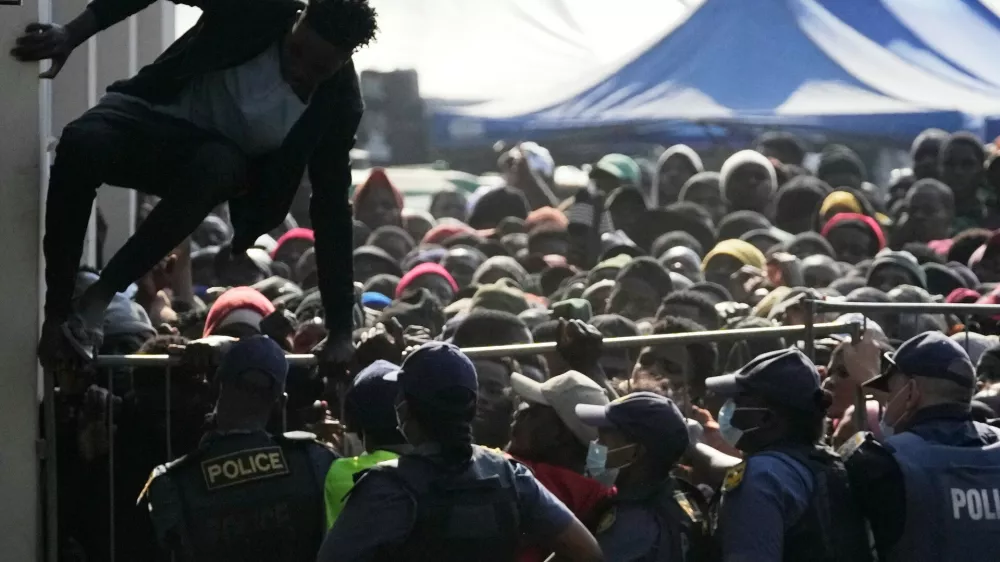 FILE - A Malawian migrant jumps over a barricade as the police officer manage the queue for their deportation at a temporary centre, in Durban, South Africa, Thursday, June 18, 2026. (AP Photo/Themba Hadebe, File)