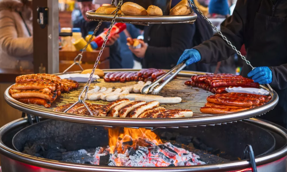 Grilling sausages on barbecue grill at a food stall of Christmas market winter wonderland in London