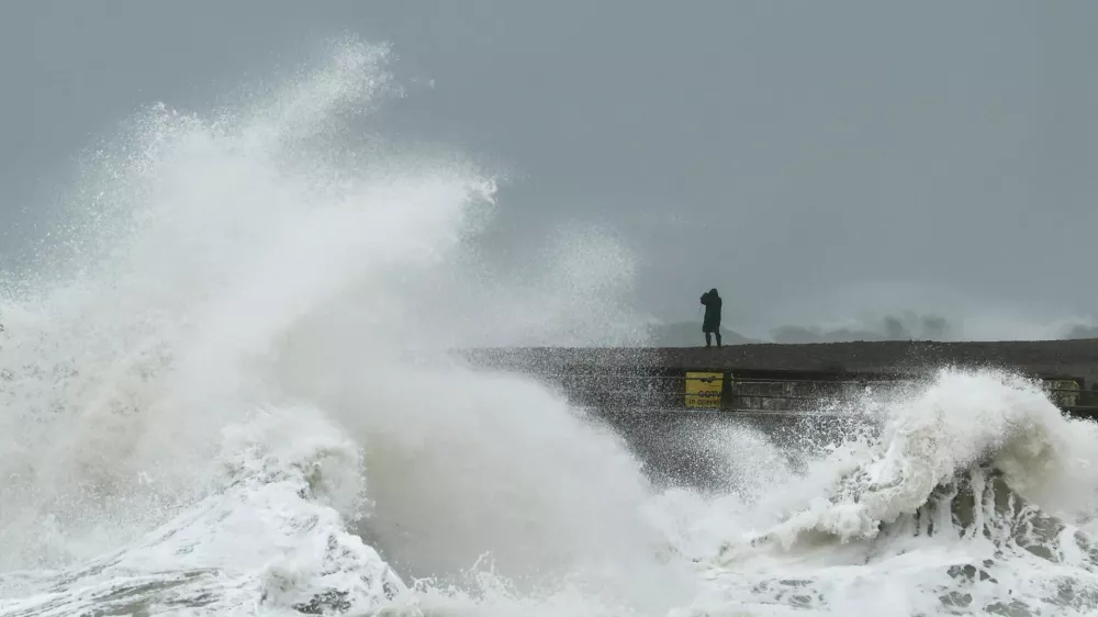 A person watches from the beach as waves crash onto Newhaven Harbour during Storm Austen in Newhaven, Britain, October 23, 2026. REUTERS/Toby Melville