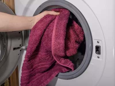 Putting a dirty towel into the washing machine close up