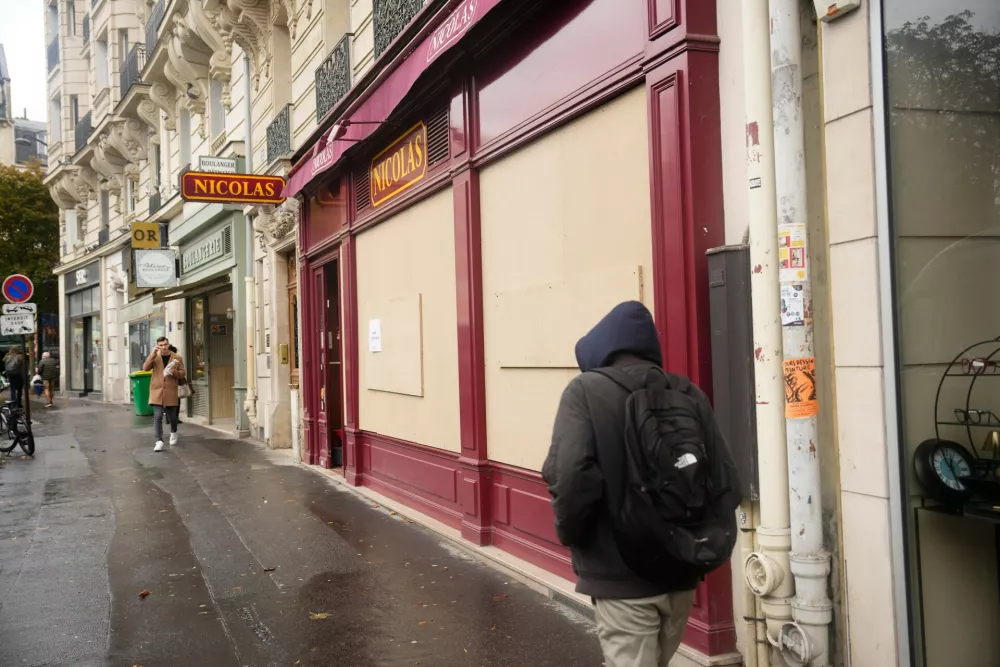 Passersby walk past a boarded-up store on the eve of a demonstration against rising living costs in Paris, Friday, Oct. 23, 2026. (AP Photo/Teresa Suarez)