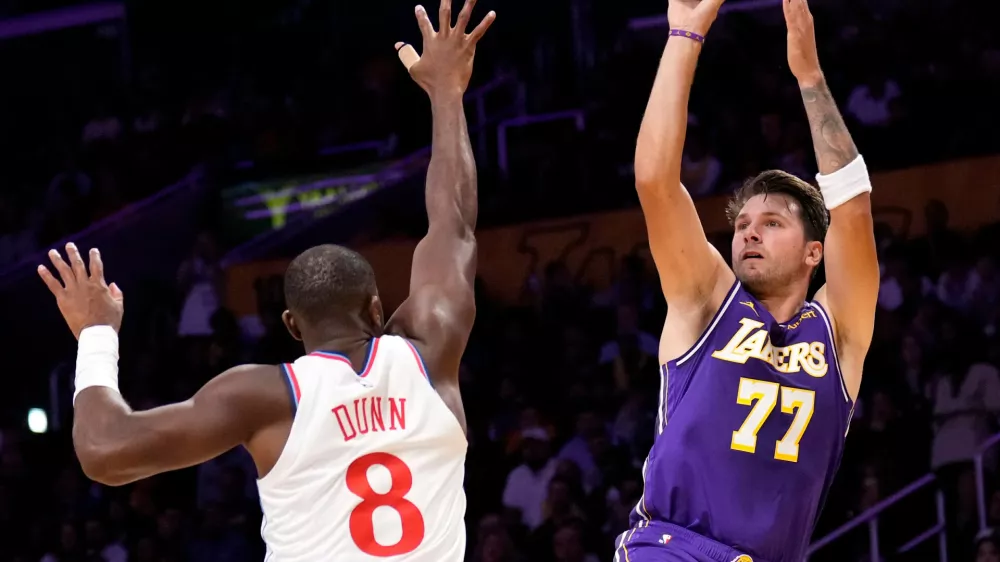Los Angeles Lakers guard Luka Doncic, right, shoots as LA Clippers guard Kris Dunn defends during the first half of an NBA basketball game Friday, Oct. 23, 2026, in Los Angeles. (AP Photo/Mark J. Terrill)