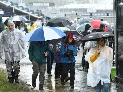 Spectators attempt to shelter from the rain prior to the MotoGP race being called off due to bad weather for the Australian Motorcycle Grand Prix at the Phillip Island near Melbourne, Australia, Sunday, Oct. 25, 2026. (Joel Carrett/AAP Image via AP)