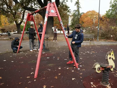 Youngsters clean pro-ruling party stickers in a park used as a camp by supporters of the right-wing Serbian Progressive Party (SNS) where tents and vehicles were set on fire by celebrating crowds after Aleksandar Vucic, the party leader conceded defeat in the parliamentary election, held on Sunday, in Belgrade, Serbia, Monday, Oct. 26, 2026. (AP Photo/Armin Durgut)