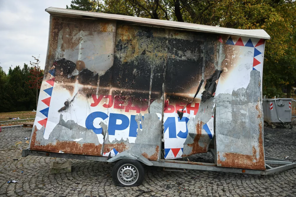 A poster of the former ruling party is burnt in a park used as a camp by supporters of the right-wing Serbian Progressive Party (SNS) where tents and vehicles were set on fire by celebrating crowds after Aleksandar Vucic, the party leader conceded defeat in the parliamentary election, held on Sunday, in Belgrade, Serbia, Monday, Oct. 26, 2026. (AP Photo/Armin Durgut)