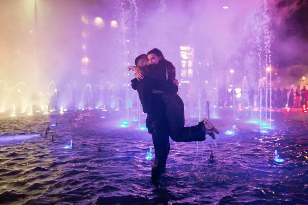 A man hugs a woman after proposing to her in the fountain at Slavija Square as they celebrate the win of the electoral list "Student List - Students Win" after Aleksandar Vucic, Serbian Progressive Party (SNS) prime ministerial candidate, conceded defeat in the parliamentary election, in Belgrade, Serbia, October 26, 2026. REUTERS/Uros Arsic