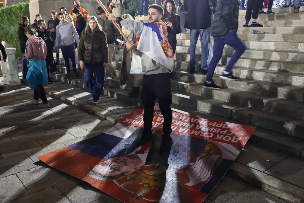 A man celebrates standing on a defaced poster of Aleksandar Vucic, leader of the right-wing Serbian Progressive Party (SNS), after he conceded defeat in the parliamentary election in Belgrade, Serbia, Sunday, Oct. 25, 2026. (AP Photo/Armin Durgut)