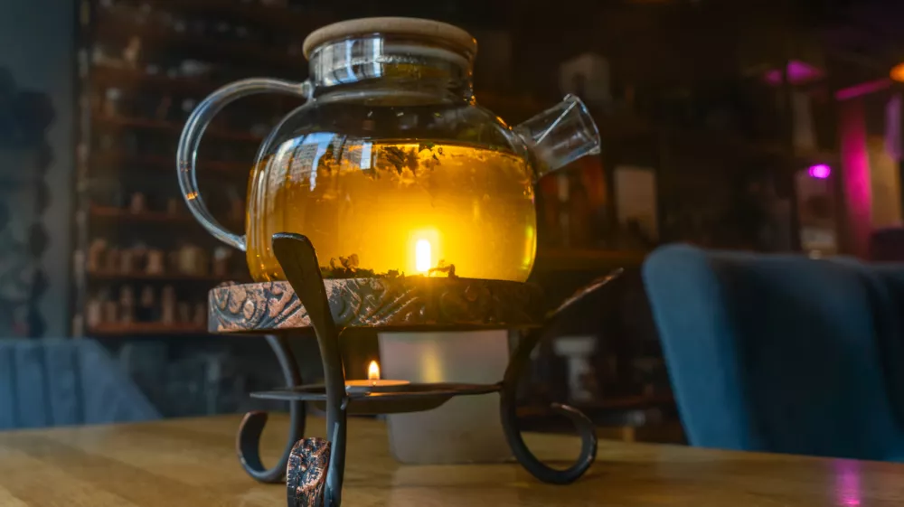 Golden hour tea ritual featuring herbal tea in a glass teapot symbolizing harmony warmth and shared moments of joy. Tranquil tea moment with herbal infusion in a clear teapot surrounded.