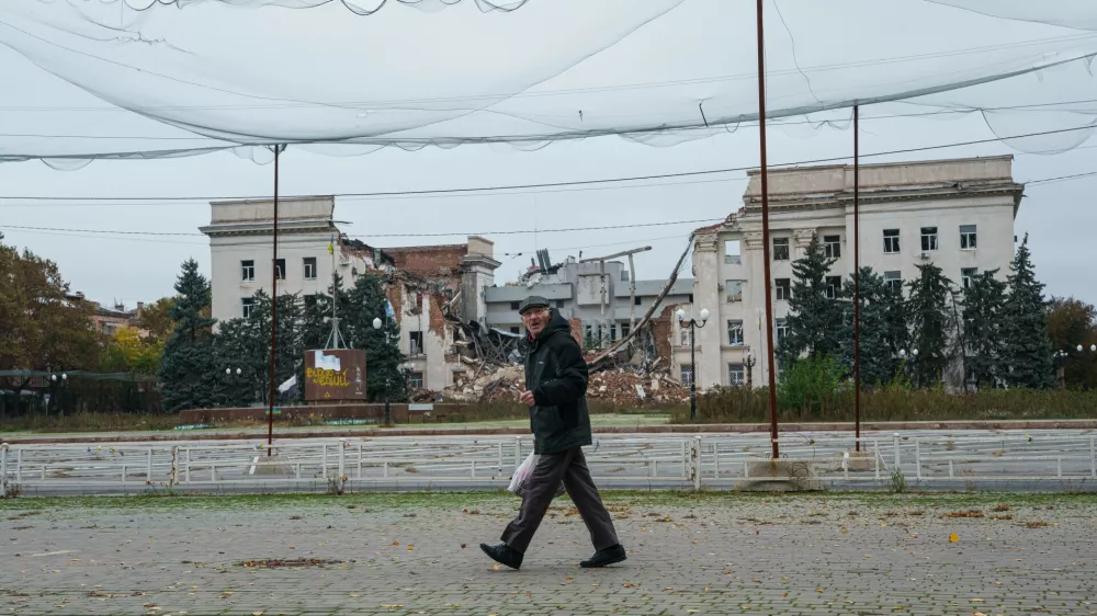 A man walks beneath anti-drone nets stretched over a street in front of a destroyed regional administration building during a local ceasefire linked to efforts to evacuate residents of Oleshky, in Kherson, Ukraine, Tuesday, Oct. 27, 2026. (AP Photo/Evgeniy Maloletka)