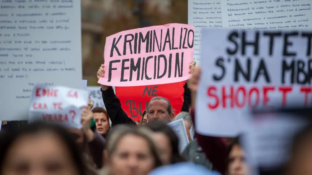 A man holds a sign "Criminalize Femicide" as thousands of people gather in Kosovo's capital to protest the killing of a Kosovo-American woman, Arlinda Zekaj, whose death sparked public outrage and renewed calls for accountability over violence against women in capital Pristina, Kosovo, on Wednesday, Oct.28, 2026. (AP Photo/Visar Kryeziu)