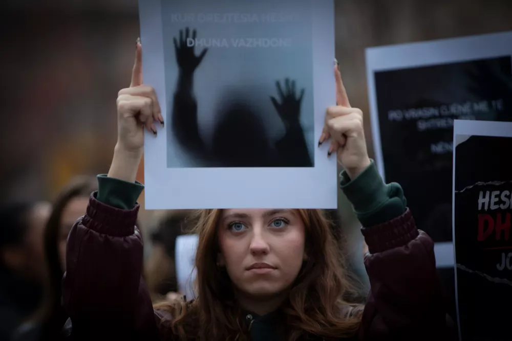 A woman holds a photo as thousands of people gather in Kosovo's capital to protest the killing of a Kosovo-American woman, Arlinda Zekaj, whose death sparked public outrage and renewed calls for accountability over violence against women in capital Pristina, Kosovo, on Wednesday, Oct.28, 2026. (AP Photo/Visar Kryeziu)