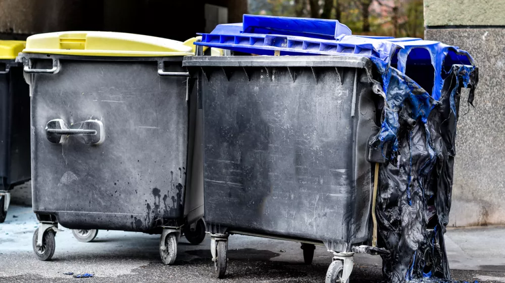 Burnt and melted trash can form a fire. Burned trash in waste container in the city is melted due to hot fire inside.