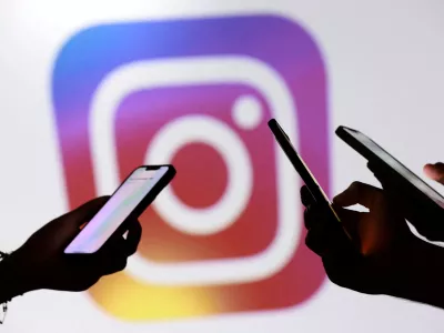 FILE PHOTO: Teenagers pose for a photo while holding smartphones in front of a Facebook logo in this illustration taken September 11, 2025. REUTERS/Dado Ruvic/Illustration/File Photo