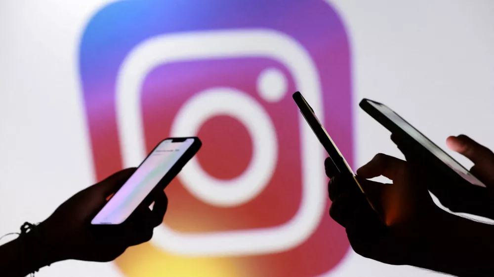FILE PHOTO: Teenagers pose for a photo while holding smartphones in front of a Facebook logo in this illustration taken September 11, 2025. REUTERS/Dado Ruvic/Illustration/File Photo