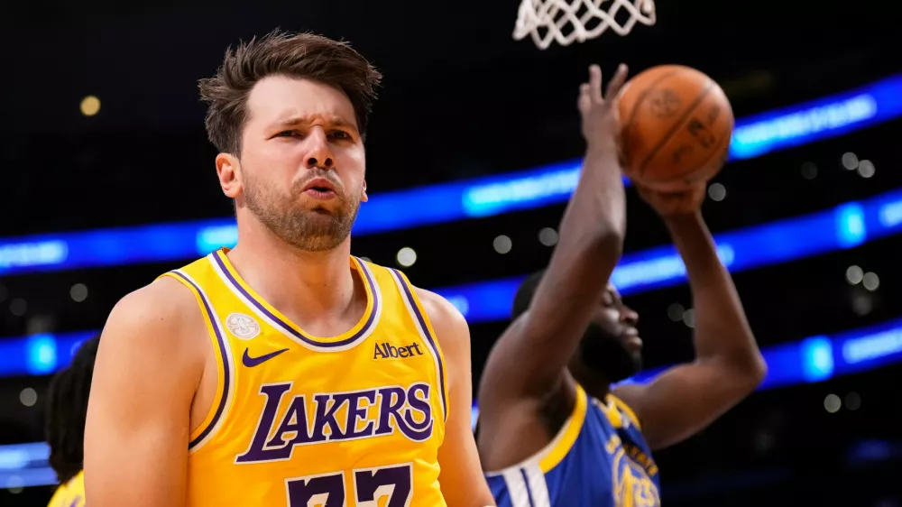Los Angeles Lakers forward/guard Luka Doncic, left, looks to fans after scoring as Golden State Warriors forward/center Draymond Green takes the ball during the first half of an NBA basketball game Wednesday, Oct. 21, 2026, in Los Angeles. (AP Photo/Mark J. Terrill)