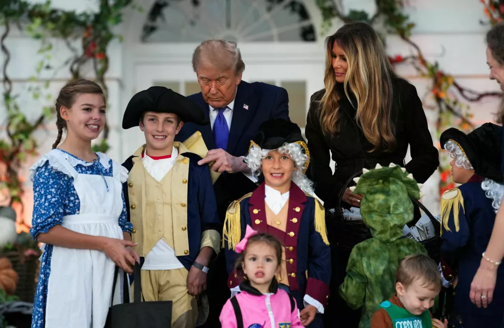 US President Donald Trump signs a paper next to first lady Melania Trump as they host a Halloween event at the White House in Washington, DC, US, October 29, 2026. REUTERS/Eric Lee