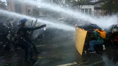 FILE PHOTO: Protesters take cover behind a plywood board as French riot police and gendarmes use a water canon amid clashes during an authorised demonstration organised by labour unions in Paris as part of nationwide protests called by the "Yellow Vests" movement joined by French high school and university students against the cost of living and rising fuel prices, in France, October 24, 2026. REUTERS/Hannah McKay   TPX IMAGES OF THE DAY/File Photo