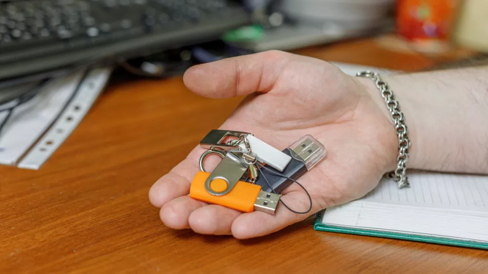 different USB flash drives are in the man's hand.