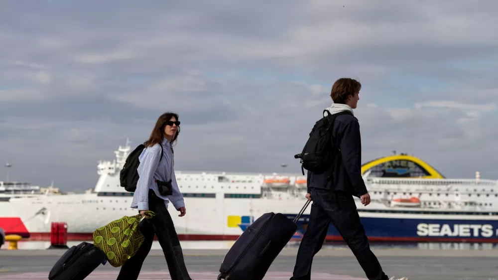 Passengers walk through the port of Piraeus during a 24-hour seafarers' strike over pay, working conditions and safety, alongside protests by port workers against the transport of military equipment through ports, near Athens, Greece, Friday, Oct. 30, 2026. (AP Photo/Thanassis Stavrakis)