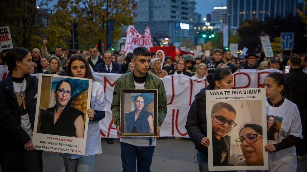 Family members of Arlinda Zekaj hold her picture during a protest in Pristina, Kosovo, as thousands gather to condemn the killing of the Kosovo-American woman, whose death sparked public outrage and renewed calls for accountability over violence against women, on Wednesday, Oct. 28, 2026. (AP Photo/Visar Kryeziu)