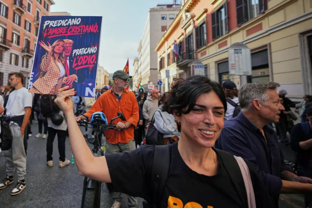 A demonstrator holds a placard depicting Italian Premier Giorgia Meloni and U.S. President Donald Trump reading "They preach Christian love, they practice hatred" during a nationwide general strike called by grassroots unions to protest rising living costs, low wages and military spending in Rome, Friday, Oct. 30, 2026. (AP Photo/Alessandra Tarantino)
