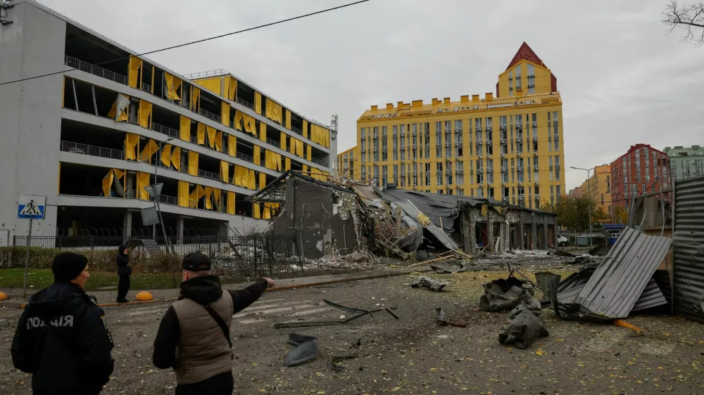 Residents and a police officer stand at the site of a residential area hit by a late evening Russian missile strike, amid Russia's attack on Ukraine in Kyiv, Ukraine October 30, 2026. REUTERS/Valentyn Ogirenko