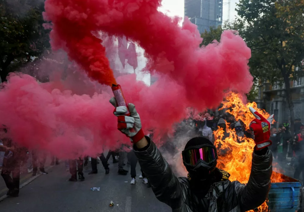 A protester wearing a mask holds a flare next to a burning baricade during an anti-government protest in Tirana, Albania, October 31, 2026. REUTERS/Florion Goga